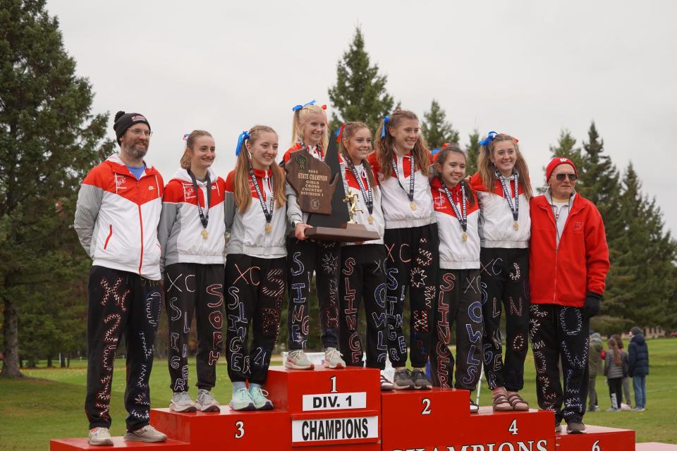 The Slinger girls cross country teams poses with coaches John Strand (far left) and Terry Krall (far right) with the WIAA Division 1 girls state cross country trophy after the Owls' win at The Ridges Golf Course in Wisconsin Rapids on Saturday Oct. 28, 2023.