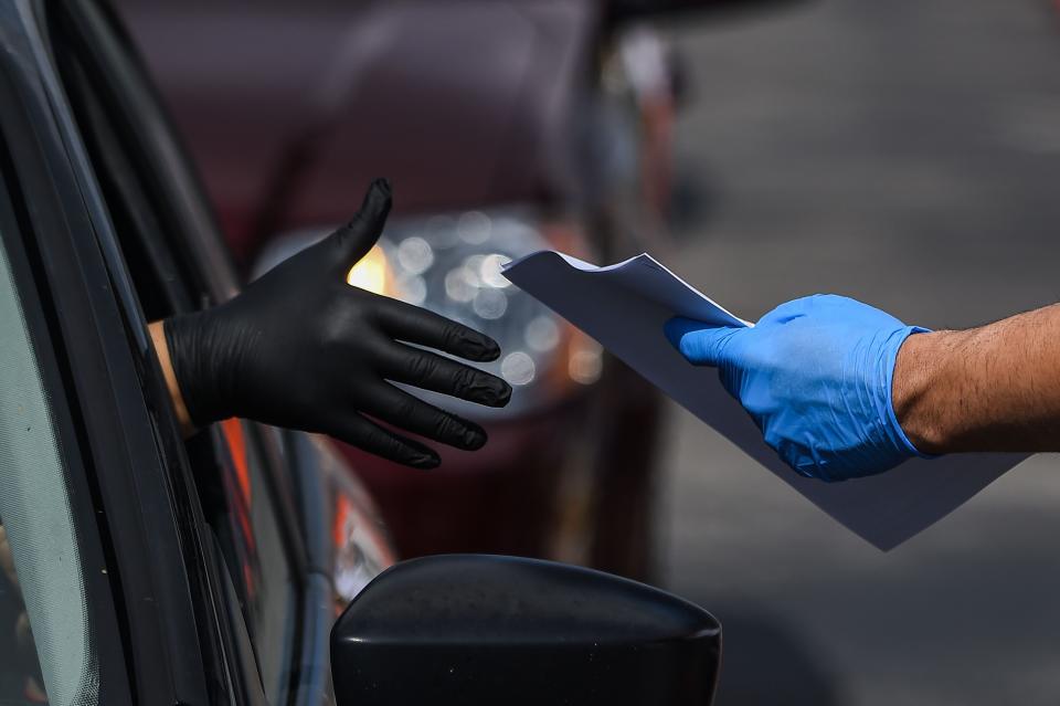 A man collects unemployment forms at a drive through collection point outside John F. Kennedy Library in Hialeah, Florida, on April 8, 2020.