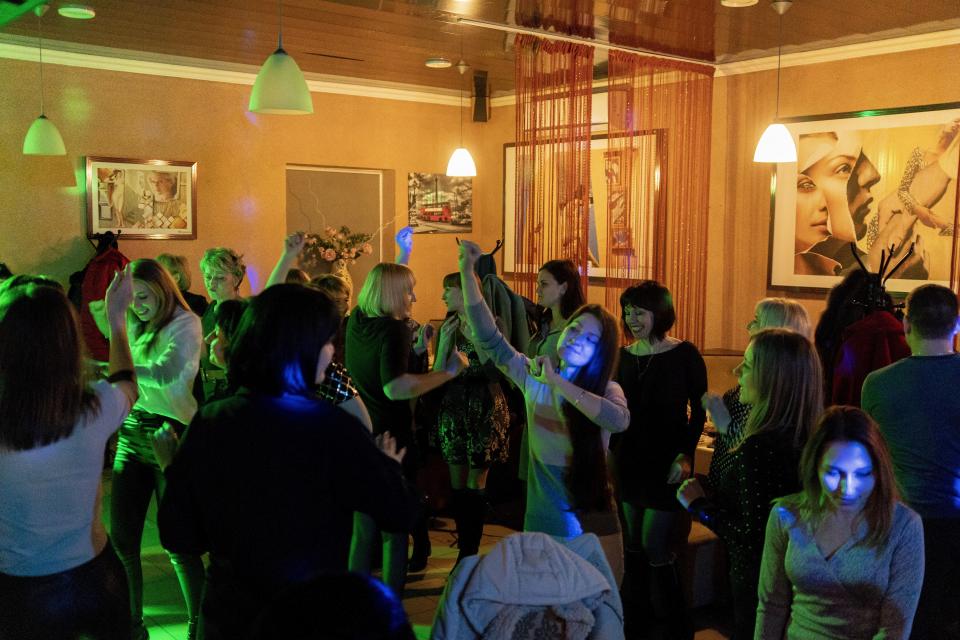 Women dance in a restaurant during a corporate celebration of International Women's Day in Kurahove, eastern Ukraine, Friday, March 5, 2021. Ukrainians are becoming increasingly opposed to vaccination: an opinion poll this month by the Kyiv International Institute of Sociology found 60% of the country's people don't want to get vaccinated, up from 40% a month earlier. (AP Photo/Evgeniy Maloletka)