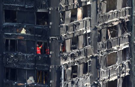 FILE PHOTO - Members of the emergency services work inside burnt out remains of the Grenfell apartment tower in North Kensington, London, Britain, June 18, 2017. REUTERS/Neil Hall/File Photo