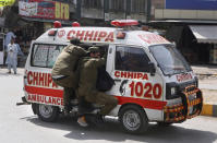 Police officers hang on to an ambulance carrying their colleagues that were injured during a clash with supporters of Tehreek-e-Labiak Pakistan, a banned Islamist party, protesting the arrest of their party leader Saad Rizvi, in Lahore, Pakistan, Sunday, April 18, 2021. A crackdown by security forces on protesting supporters of the banned party left several people dead and many others, including police officers, injured, a police spokesman said Sunday. (AP Photo/K.M. Chaudary)