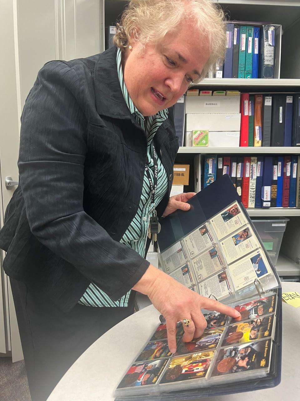 Carrie Cavanaugh, director of the Center for Active Adults in South Lyon, shows some of the race car driver cards, including John Andretti, in the 88,500 trading card collection donated to the center.