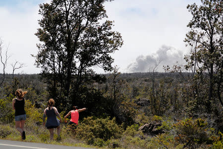 With an ash cloud visible from the Halemaumau crater, onlookers are seen from Highway 11 during the eruption of the Kilauea Volcano near Volcano, Hawaii, U.S., May 23, 2018. REUTERS/Marco Garcia