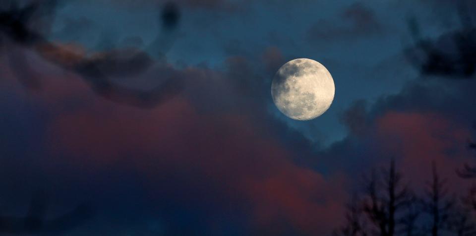 The full moon rises above a cloud bank tinted pink by the last light of the day Thursday, Feb. 25, 2021 over Northport, Alabama.