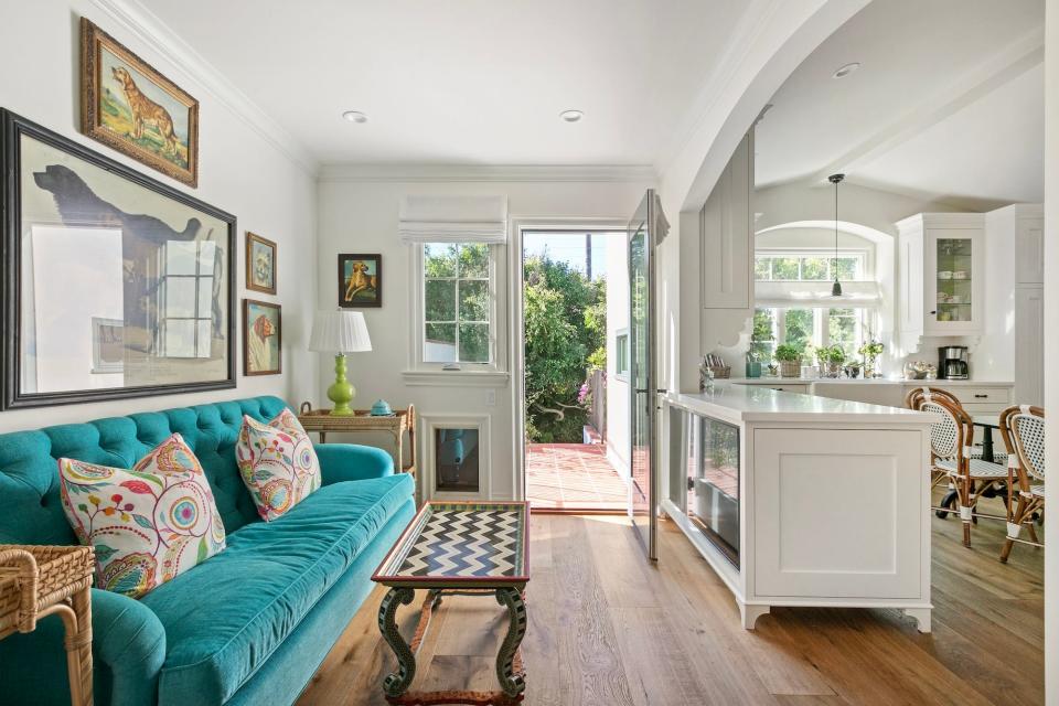 A living area with a teal couch that leads to a patio.