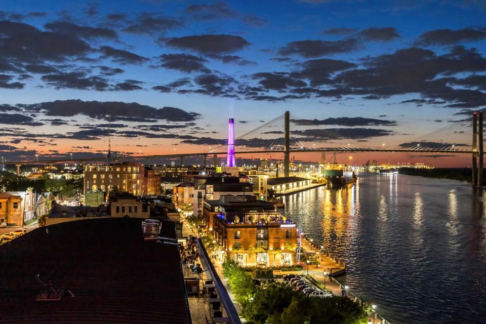 Savannah Georgia skyline at dusk from the top of a roof deck with the river water, bridge and buildings