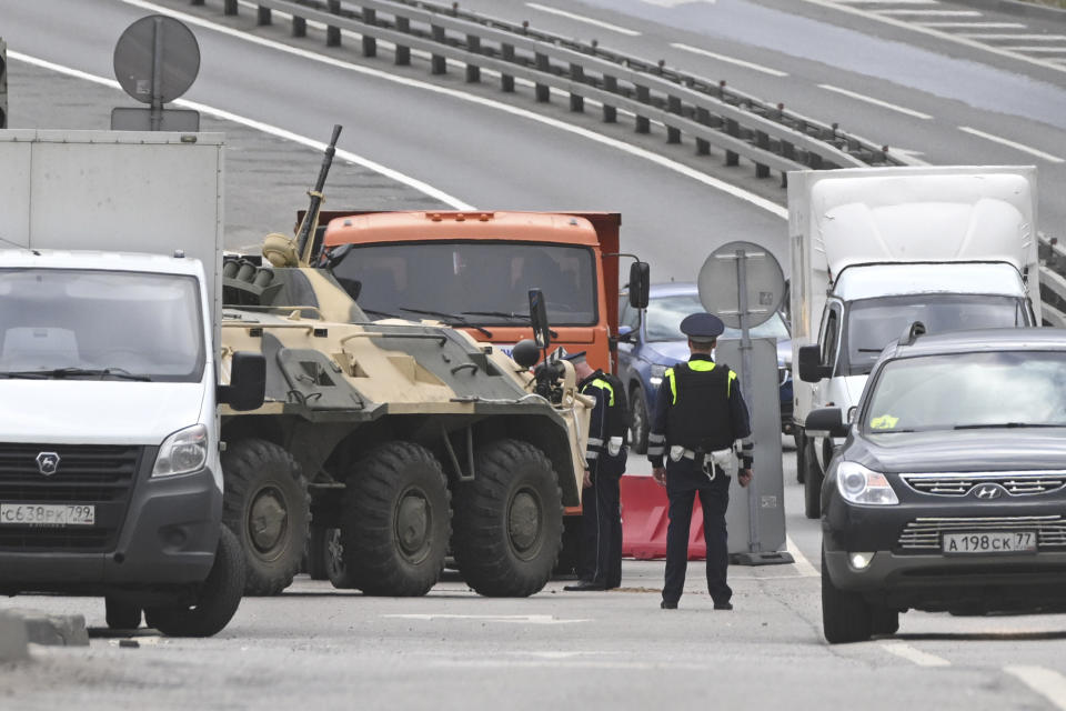 FILE - An APC and road police officers stand on the highway at the entrance to Moscow, Russia, Saturday, June 24, 2023. A week after the mutiny raised the most daunting challenge to President Vladimir Putin’s rule in over two decades, key details about the uprising remain shrouded in mystery. (AP Photo, File)