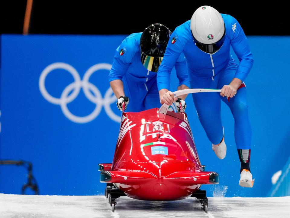 Two man bobsledders in red bobsled at Beijing Olympics