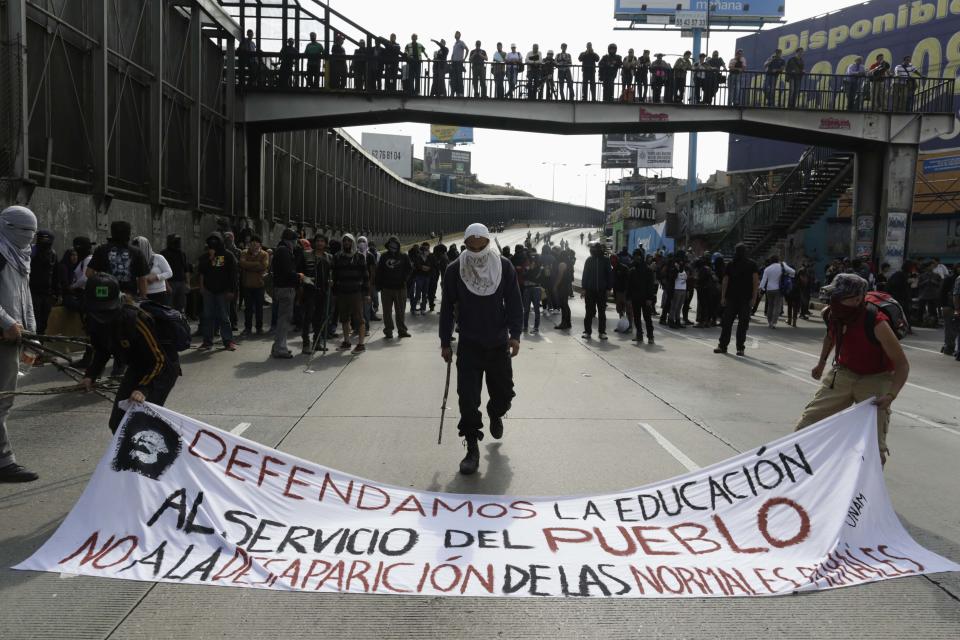 Masked demonstrators block an access road to the Benito Juarez International airport during a protest over the 43 missing Ayotzinapa students in Mexico City