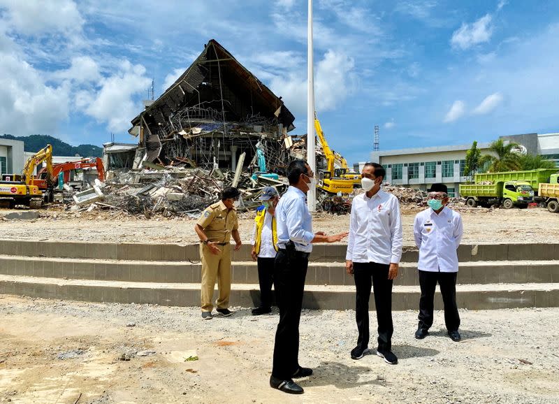 Indonesian President Joko Widodo talks with an official during a visit inspecting the area affected by the earthquake in Mamuju