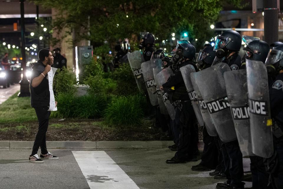 A protest talks to the Detroit police officers in riot gear on Jefferson Avenue after an afternoon march and rally against police brutality extended into the evening and became contentious on Friday, May 29, 2020 in Detroit.