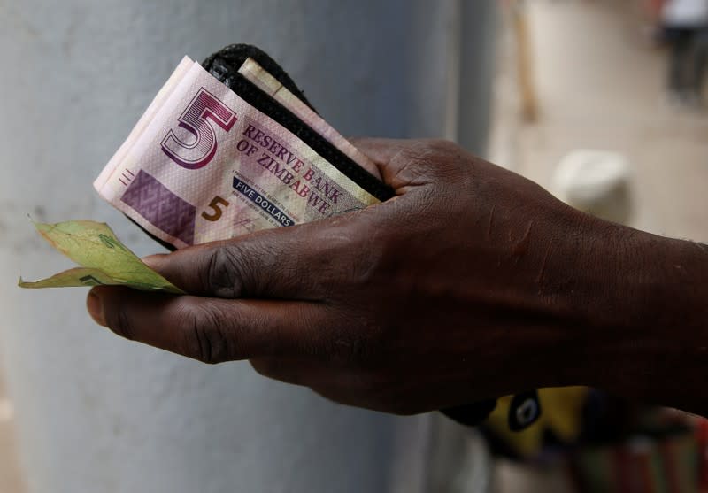 A street vendor poses as he displays bond notes, before the introduction of new currency in Harare