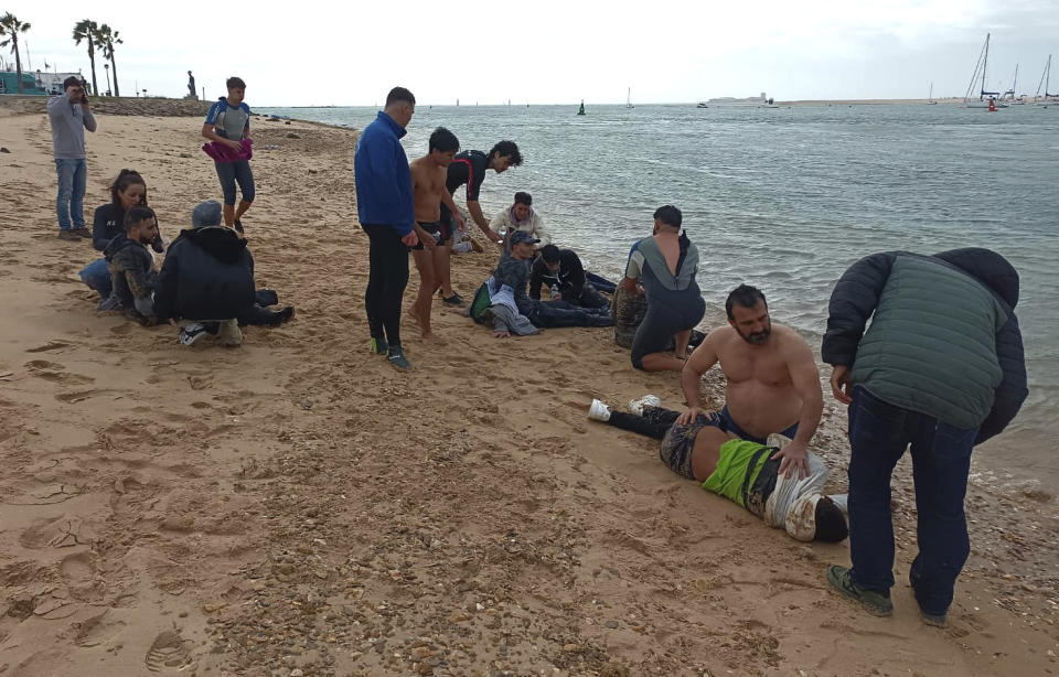 Migrants are rescued by locals on the shore of a beach, close to the southwestern city of Cádiz, Spain, Thursday, Nov. 30, 2023. Four migrants have died meters (yards) from shore in southern Spain after being forced out of the boat they were traveling in, officials said Thursday. The Spanish government press office in the southern province of Cádiz said 31 other people from the boat, including six children, survived the Wednesday afternoon incident and four were taken to a hospital. (AP Photo/Jorge Gonzalez Casares)