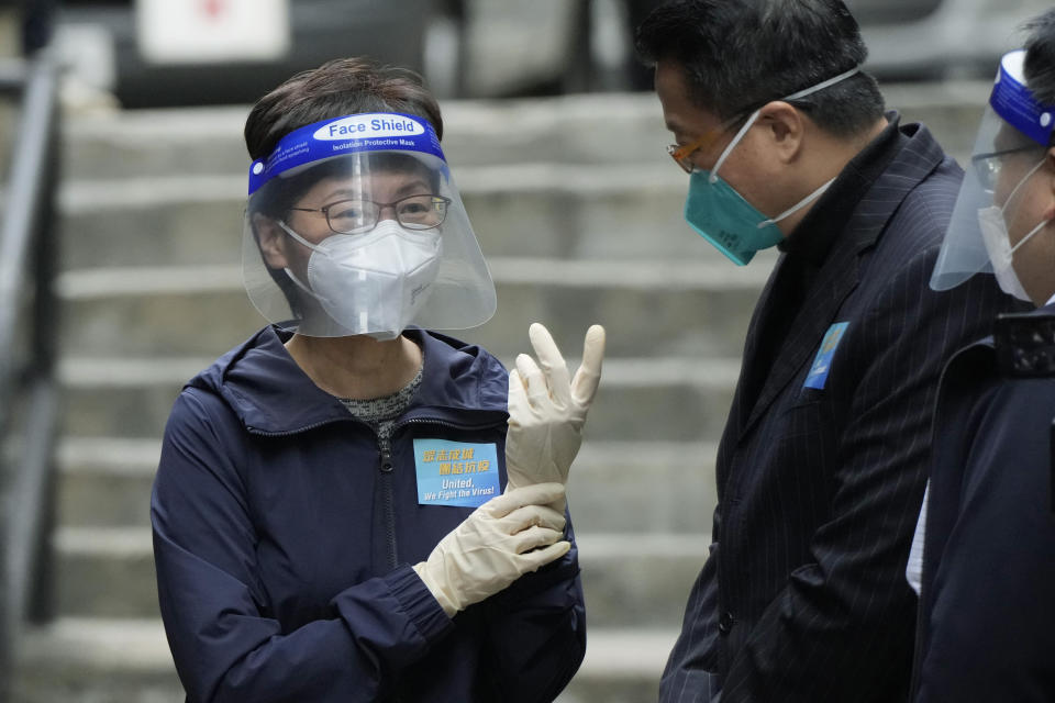 Hong Kong Chief Executive Carrie Lam, left, wears gloves before delivering package of coronavirus prevention materials to people during an anti-epidemic event in Hong Kong, Saturday, April 2, 2022. Hong Kong authorities on Saturday asked the entire population of more than 7.4 million people to voluntarily test themselves for COVID-19 at home for three days in a row starting next week. (AP Photo/Kin Cheung)