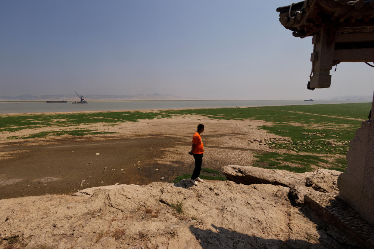 A man stands on Louxingdun island that usually remains partially submerged under the water of Poyang Lake which is facing low water levels due to a regional drought in Lushan, Jiangxi province, China, August 24, 2022.  REUTERS/Thomas Peter