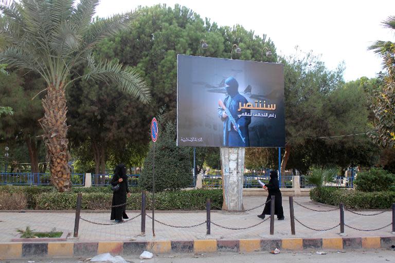 Women wearing a niqab, a type of full veil, walk under a billboard erected by the Islamic State group as part of a campaign in the IS-controlled Syrian city of Raqqa on November 1, 2014