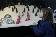 Thomasina McManus, age five, looks at toys displayed in the window of Selfridges on Oxford Street on the last Sunday before Christmas in London December 22, 2013. REUTERS/Luke MacGregor