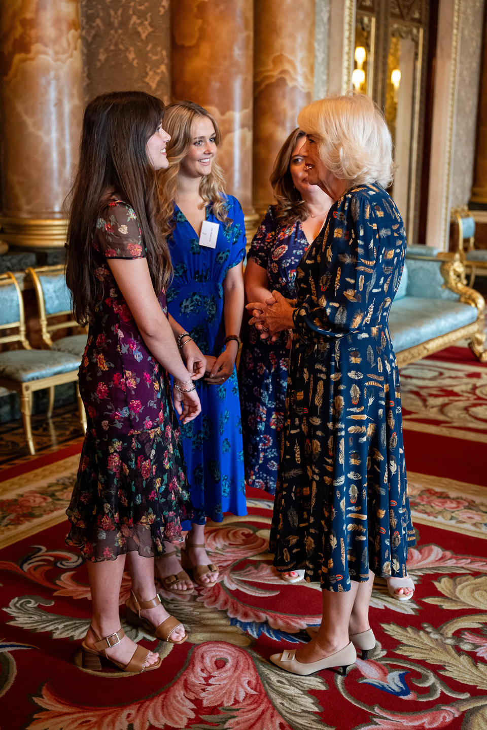 LONDON, ENGLAND - MAY 14: Queen Camilla talks with the artist's family as the portrait of the King Charles III by artist Jonathan Yeo is unveiled in the blue drawing room at Buckingham Palace on May 14, 2024 in London, England. The portrait was commissioned in 2020 to celebrate the then Prince of Wales's 50 years as a member of The Drapers' Company in 2022. The artwork depicts the King wearing the uniform of the Welsh Guards, of which he was made Regimental Colonel in 1975. The canvas size - approximately 8.5 by 6.5 feet when framed - was carefully considered to fit within the architecture of Drapers' Hall and the context of the paintings it will eventually hang alongside. Jonathan Yeo had four sittings with the King, beginning when he was Prince of Wales in June 2021 at Highgrove, and later at Clarence House. The last sitting took place in November 2023 at Clarence House. Yeo also worked from drawings and photographs he took, allowing him to work on the portrait in his London studio between sittings. (Photo by Aaron Chown-WPA Pool/Getty Images)
