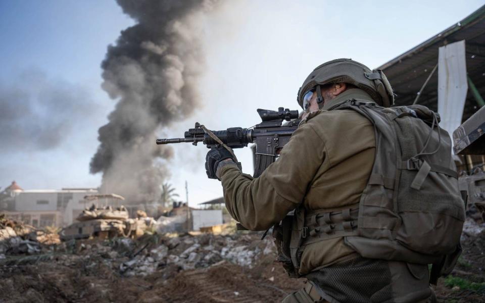 Above ground, a soldier trains his rifle as a column of smoke rises in the air behind him