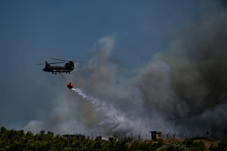 Un hélicoptère largue une cargaison d'eau sur un feu de forêt à Keratea, près d'Athènes, le 30 juin 2024 en Grèce (Aris MESSINIS)