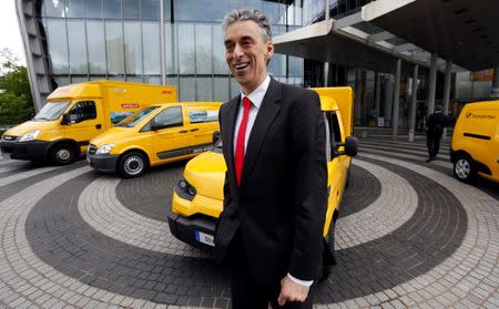 Frank Appel, CEO of German postal and logistics group Deutsche Post DHL poses in front of a StreetScooter E-car and other E-cars in Bonn May 21, 2013. REUTERS/Wolfgang Rattay/File Photo