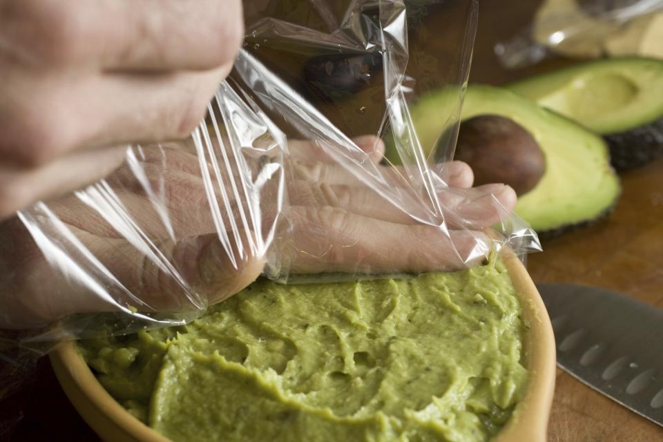 FILE - Guacamole is covered in plastic wrap in Concord, N.H., on Jan. 24, 2010, to keep it fresh by preventing air from getting to the avocado until it's time to serve. Preparing and keeping foods at the right temperature, avoiding cross contamination -- no double dipping! -- and being mindful about leaving out perishable snacks like chicken wings, meatballs and veggie platters are all keys to avoiding illness at your Super Bowl party, health experts said. (AP Photo/Larry Crowe, File)