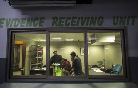 A police officer talks to a member of the evidence receiving unit at Punjab Forensic Science Agency in Lahore January 13, 2015. REUTERS/Zohra Bensemra