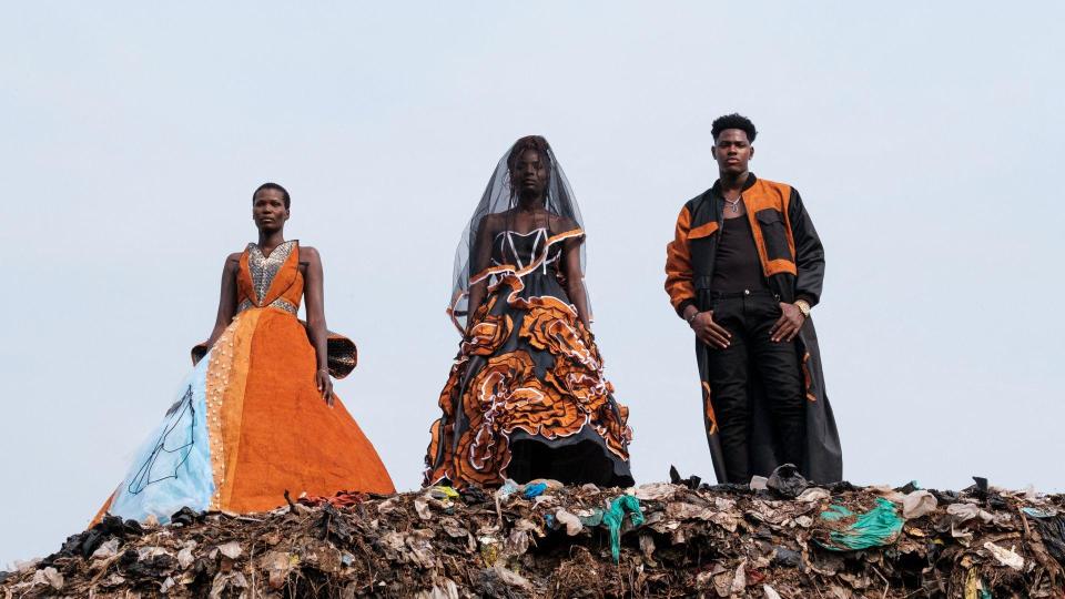 Models wearing black and orange clothes on top of a pile of rubbish in Kampala, Uganda - Saturday, July 20, 2024