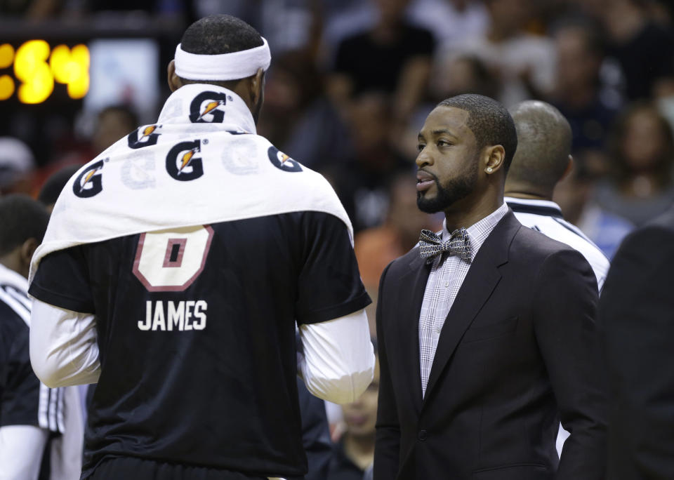 Miami Heat's Dwyane Wade, right, talks with LeBron James during the first half of an NBA basketball game against the Indiana Pacers, Friday, April 11, 2014, in Miami. Wade did not play due to a hamstring injury. (AP Photo/Lynne Sladky)