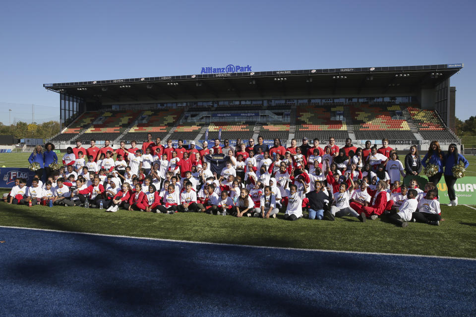 Local schoolchildren pose for a picture during an NFL Flag football event before a training session at Allianz Park in London, Friday Oct. 19, 2018. The Los Angeles Chargers are preparing for an NFL football game against the Tennessee Titans at London's Wembley stadium on Sunday. (AP Photo/Tim Ireland)