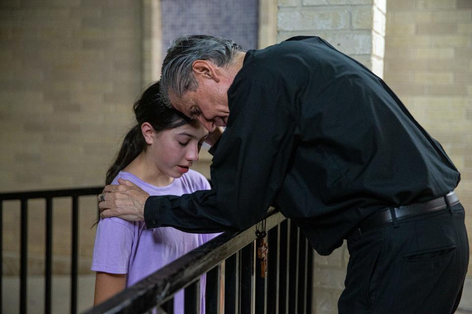 Archbishop of the Archdioceses of San Antonio Gustavo Garcia-Siller prays with Catherine Spurgers, 15, of Uvalde, Texas, outside Sacred Heart Church on May 24.