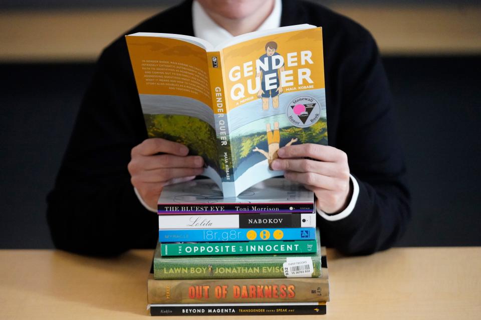 Amanda Darrow, director of youth, family and education programs at the Utah Pride Center, poses with books that have been the subject of complaints from parents in recent weeks on Thursday, Dec. 16, 2021, in Salt Lake City. Community leaders in Utah have said titles with characters and plot lines involving LGBT and minority students have been disproportionately targeted.  Darrow said books like "Beyond Magenta," "Gender Queer" and "Lawn Boy" show LGBT and minority teens that they have a place and are represented in their schools and communities.