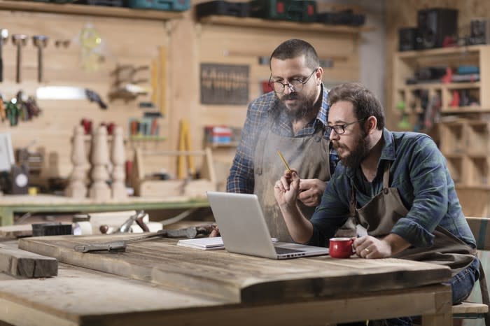 Two men in repair shop looking at laptop.