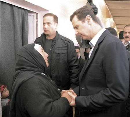 Syria's President Bashar al-Assad speaks with a woman during his visit to displaced Syrians in the town of Adra in the Damascus countryside March 12, 2014, in this handout photograph released by Syria's national news agency SANA. REUTERS/SANA/Handout via Reuters