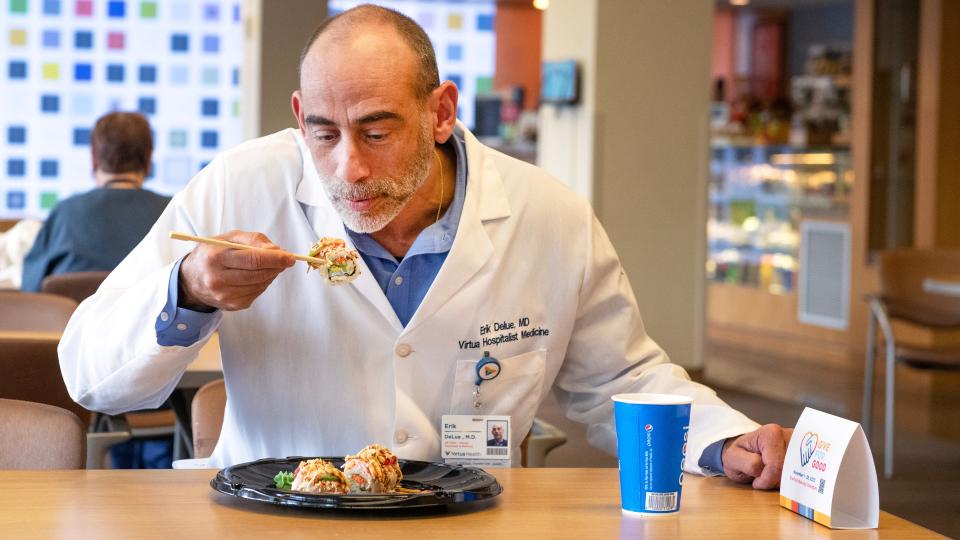 Dr. Erik DeLue dines on a freshly made sushi roll as he sits near the cafeteria in Virtua Voorhees Hospital.