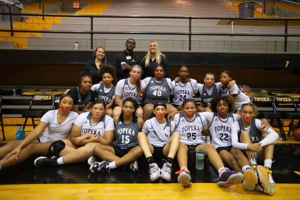 The Topeka High girls basketball team pose for a group photo Tuesday's Late Night in the Dungeon with red handprints across their faces to show support for missing and murdered Indigenous women during Native American Heritage Month.