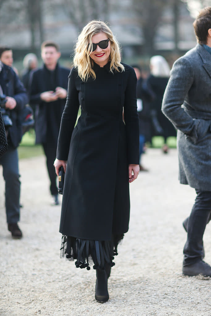 <p>Dunst wears all black arriving at the Christian Dior show in Paris. Notice the dangling details at the hem of her coat. <i>(Photo: Getty) </i></p>