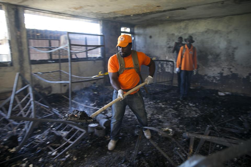 A civil protection worker shovels charred debris from inside the Orphanage of the Church of Bible Understanding where a fire broke out the previous night in Kenscoff, on the outskirts of Port-au-Prince, Haiti, Friday, Feb. 14, 2020. A fire swept through this Haitian children’s home run by a Pennsylvania-based nonprofit group, killing 13 children, health care workers said Friday. (AP Photo/Dieu Nalio Chery)