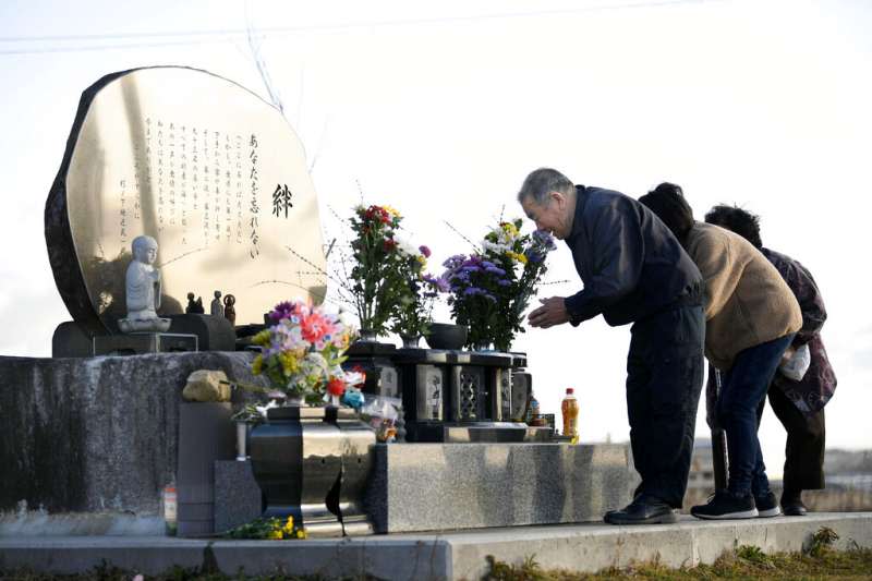<cite>日本311大震災的受害者家屬在宮城縣氣仙沼市海邊的慰靈碑前祭拜。（美聯社）</cite>