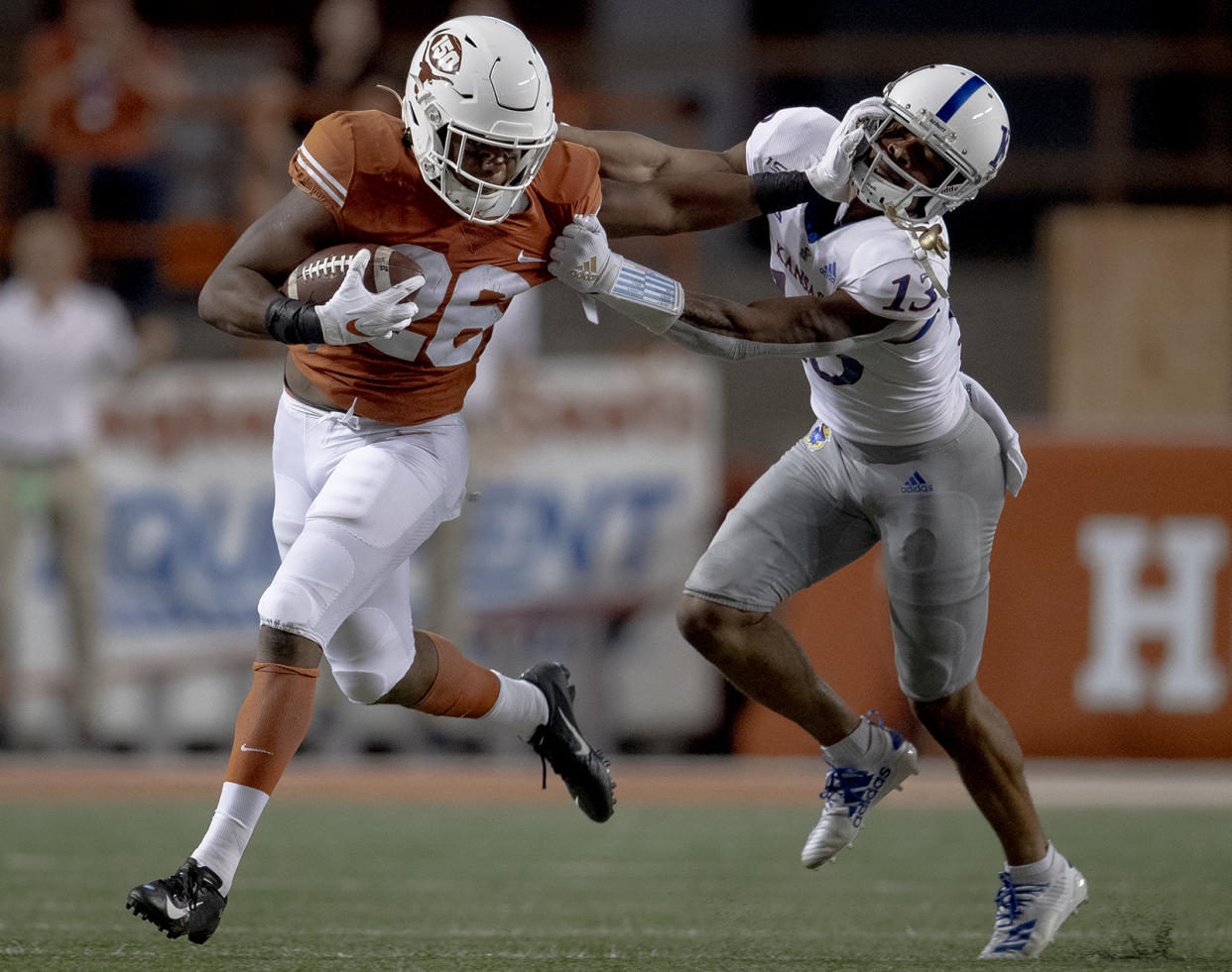 Texas running back Keaontay Ingram (26) stiff-arms Kansas cornerback Hasan Defense (13) during an NCAA college football game Saturday, Oct. 19, 2019, in Austin, Texas. (Nick Wagner/Austin American-Statesman via AP)