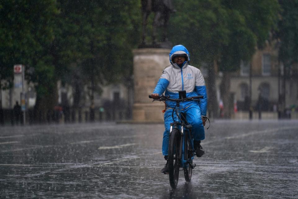 A man rides a bike along Whitehall as heavy rain sweeps through central London (Victoria Jones/PA) (PA Wire)