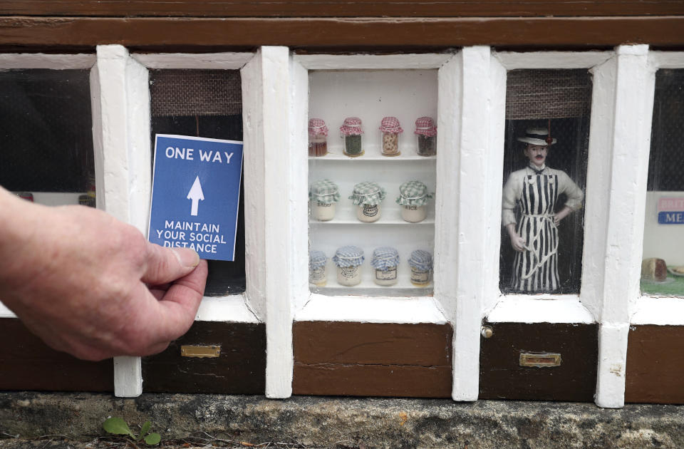 A miniature one way social distancing sign is placed in the shop front of Wilson and Son butchers at the Wimborne Model Town and Gardens, as they prepare to reopen to members of the public on Saturday following the easing of lockdown restrictions in England, in Wimborne, England, Thursday, July 9, 2020. (Andrew Matthews/PA via AP)