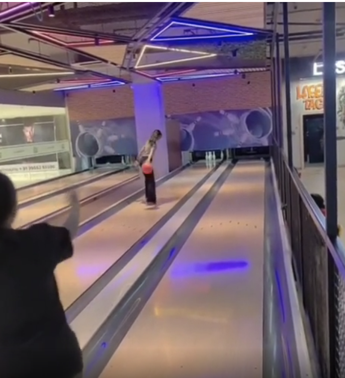 a person bowling, but standing way down the lane where they're not supposed to