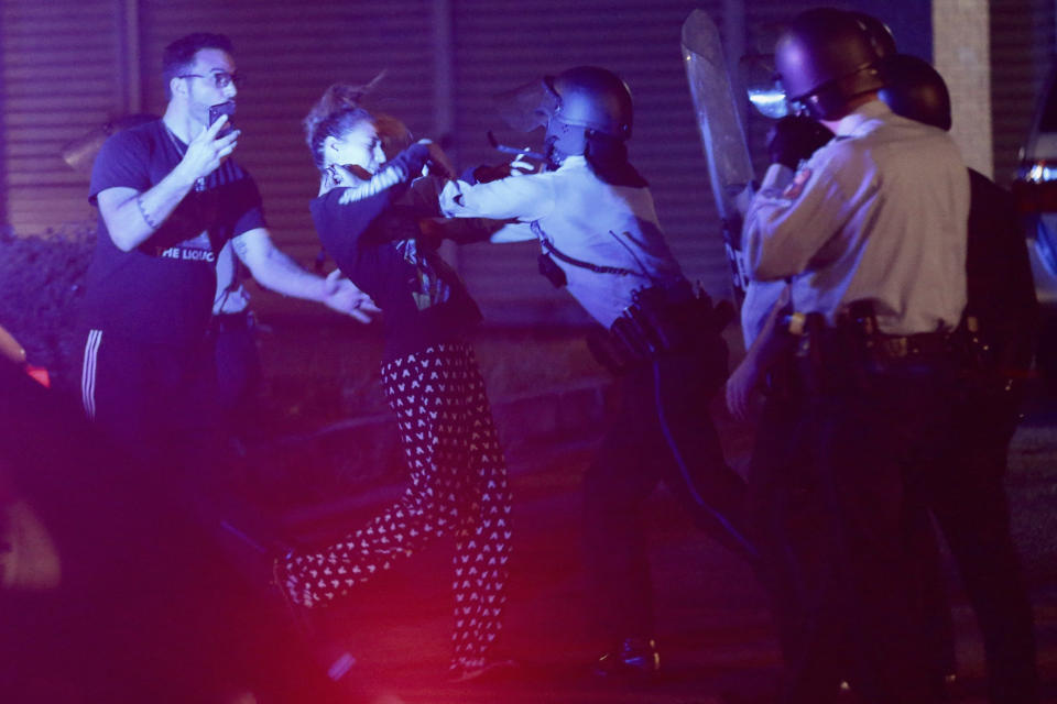 Police shove back a woman who was arguing with them just off 52nd Street in West Philadelphia in the early hours of Tuesday, Oct. 27, 2020. Protesters gathered after police shot and killed a Black man in West Philadelphia on Monday. (Tim Tai/The Philadelphia Inquirer via AP)