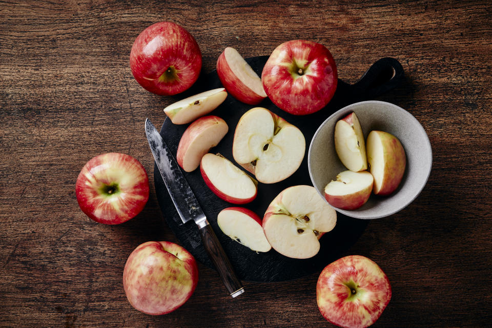 top down view of whole and cut honey crisp apples on wood table with copy space