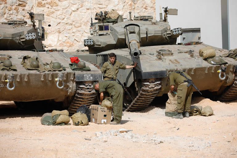 Los soldados israelíes hacen preparativos frente a los tanques Merkava mientras ocupan una posición en un lugar no revelado en la frontera con el Líbano el 22 de octubre de 2023