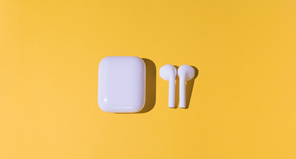 apple airpods next to airpods case on solid yellow background