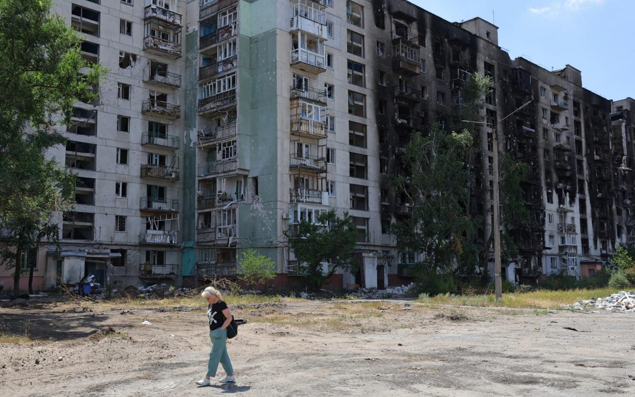 A Ukrainian resident walks alone in front of destroyed apartment block in the city of Sievierodonetsk in the Luhansk Region - ALEXANDER ERMOCHENKO 