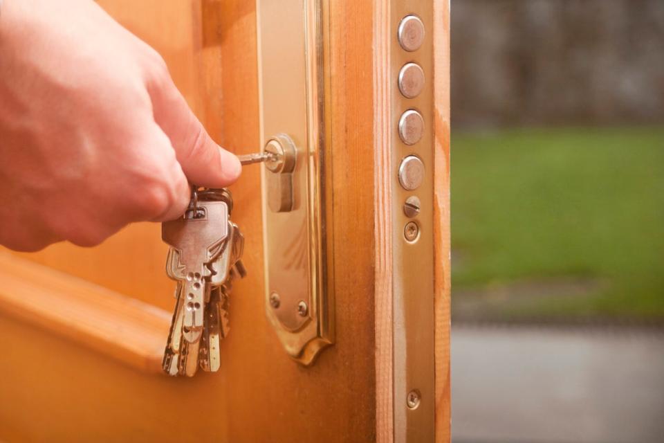 hand putting key in lock of wooden door to lock it