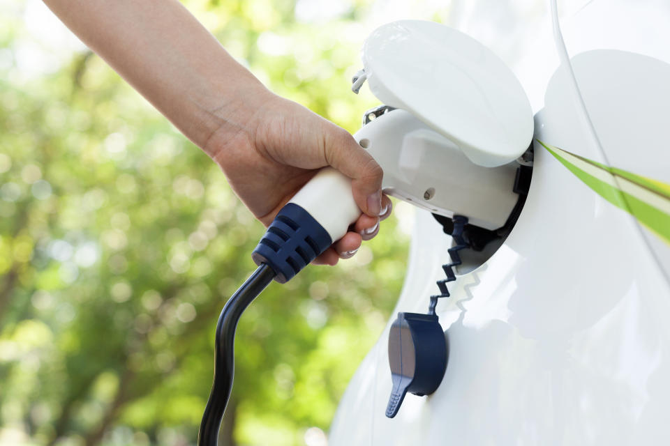 Cropped Hand Of Woman Charging Electric Car At Station